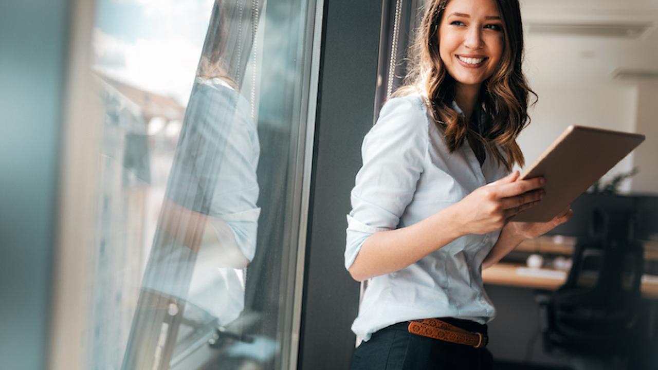 Woman in an office holding a clipboard.