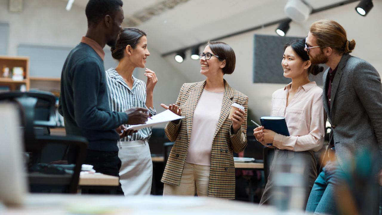 Group of five women and men at work having a discussion.