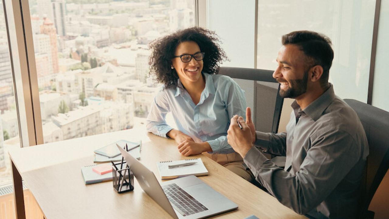 Two people at a conference room table having a discussion.