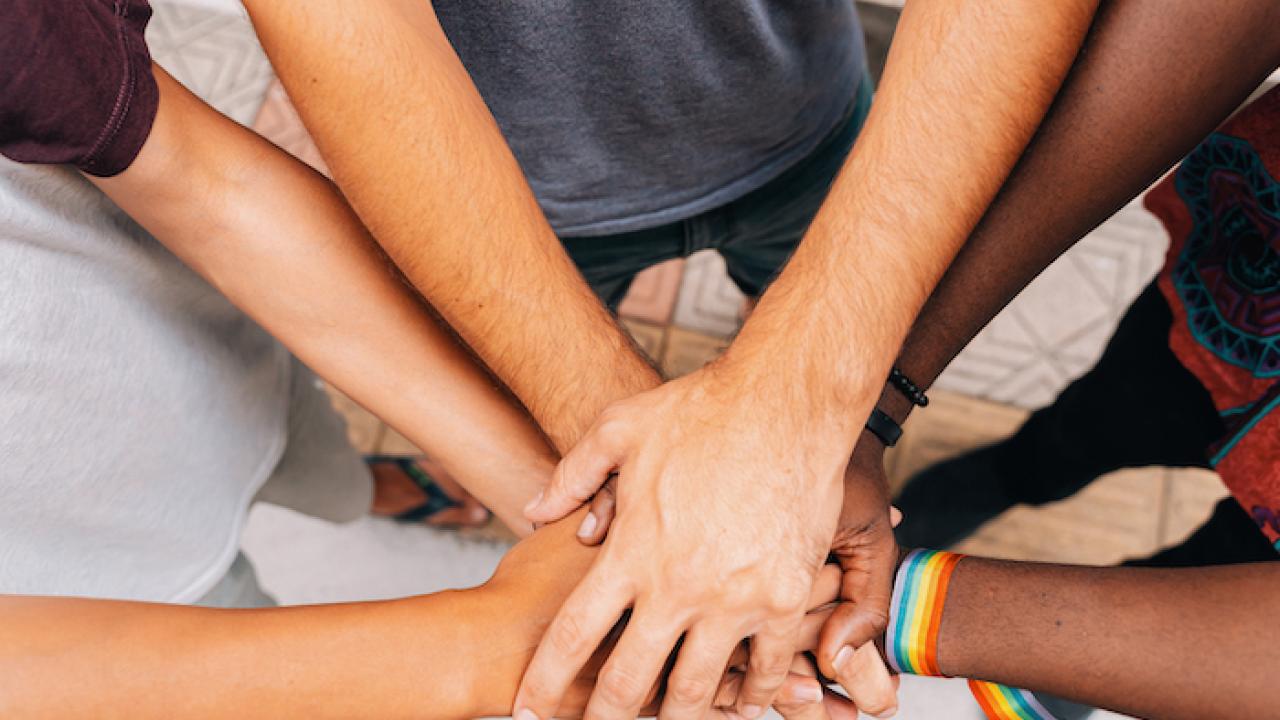 Group of black and white hands joined in the center of a circle.