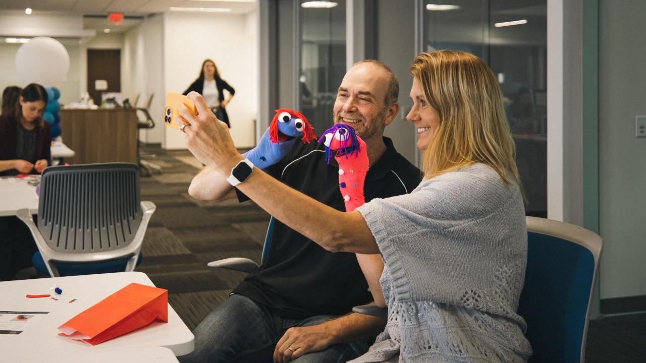 Woman and a man taking a selfie at a desk.