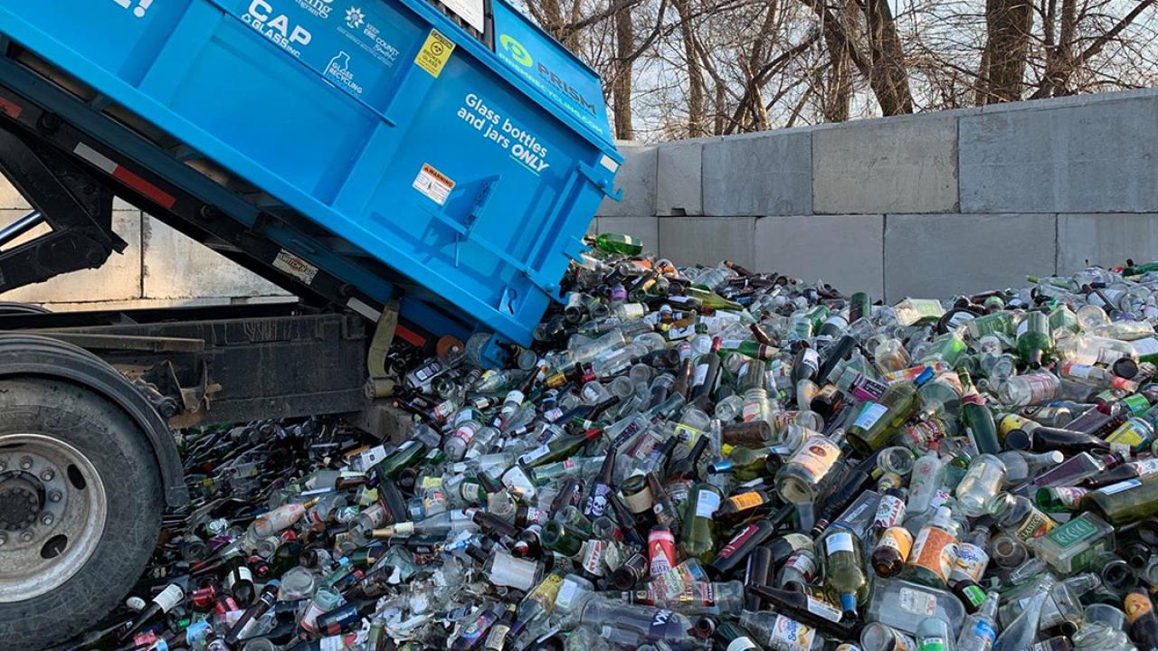 recycling truck dumping glass bottles into pile
