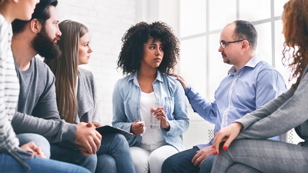 Group of employees supporting a distressed woman in the center