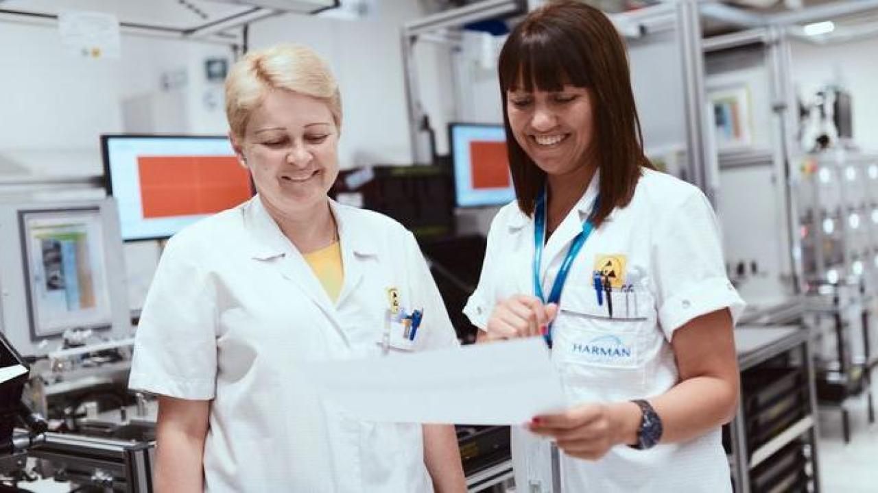 Two female technicians shown reading a report in the HARMAN labs.