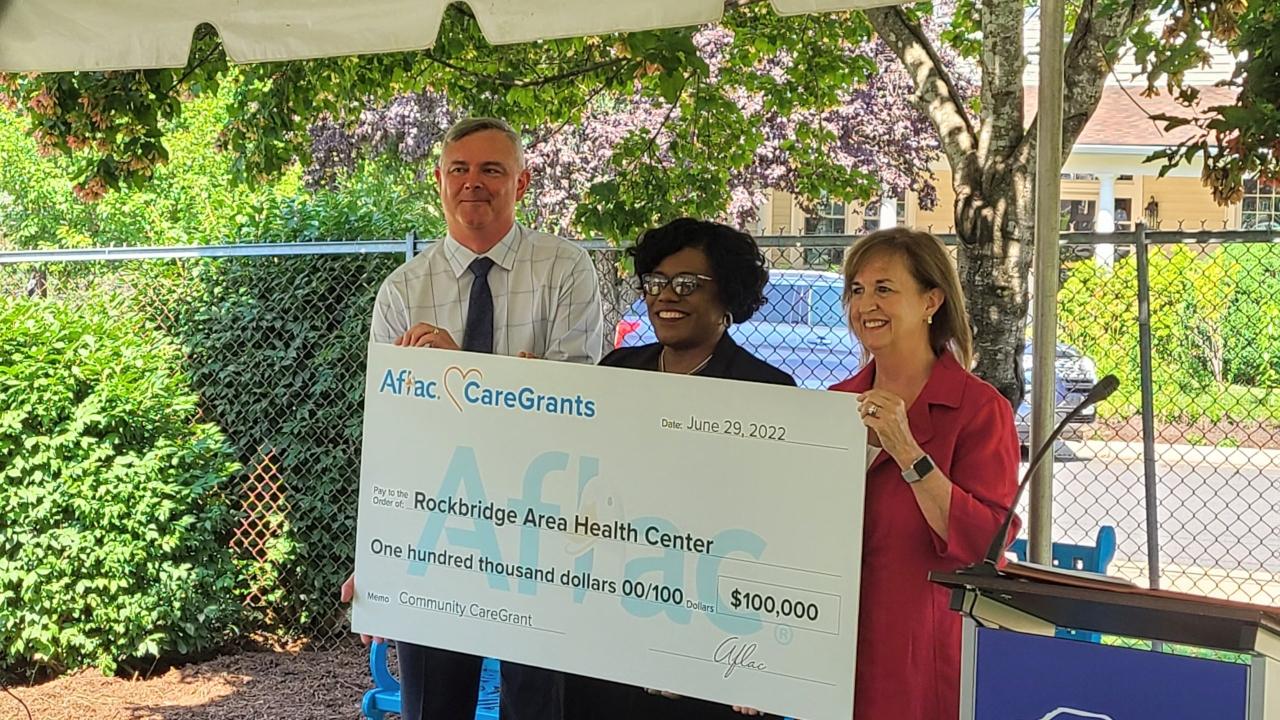 Three people holding a check at the presentation event 