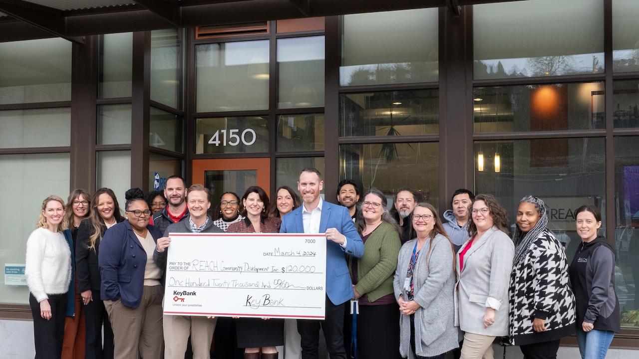Representatives from KeyBank and REACH shown with a $120,000 grant check.