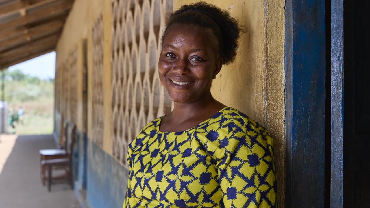 Portrait photo of Mabinty in front of the school she teaches at.
