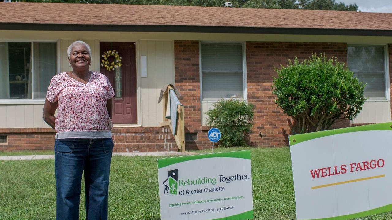 Woman stands in front of her house.