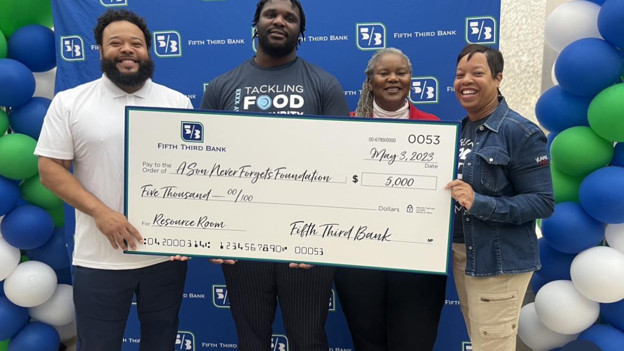 Four people holding a large Fifth Third Bank check