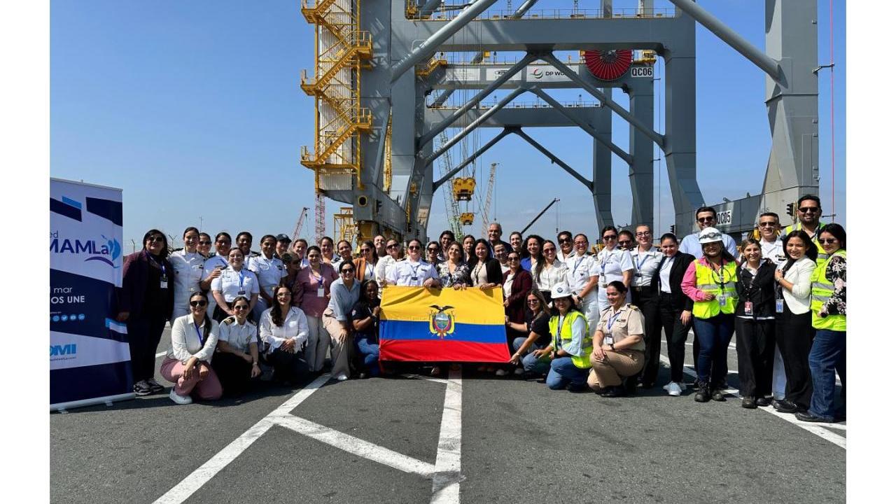 A large group of women and men stand together at a port terminal holding the Ecuadorian flag during a gender equity event with Red MAMLa.