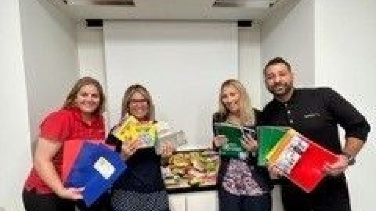 Four people stood together holding Supplies to help children and families 