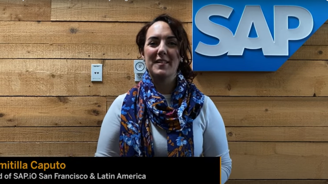 Domitilla Caputo in front of a wood-plank wall and SAP logo sign.