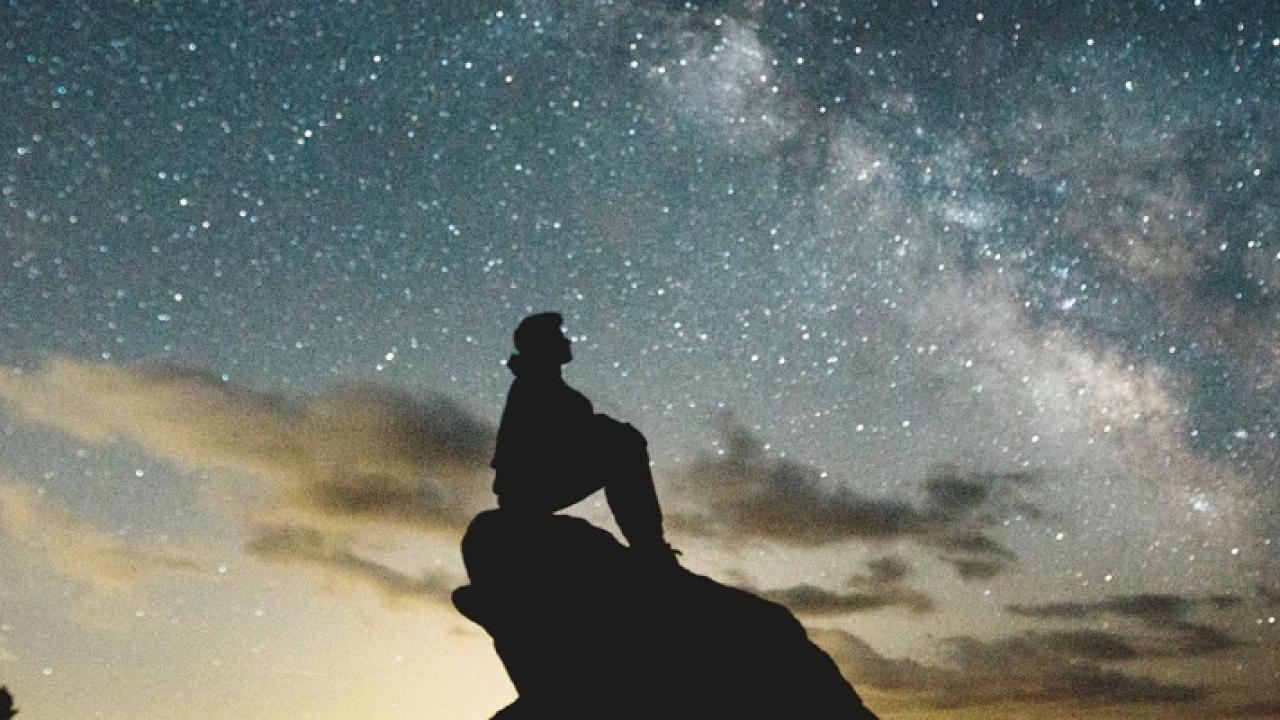 Person sitting on rock with the night sky background