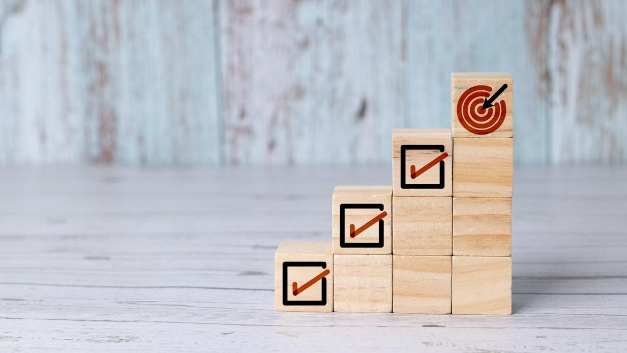 Wooden blocks with checked boxes stacked to mimic four steps