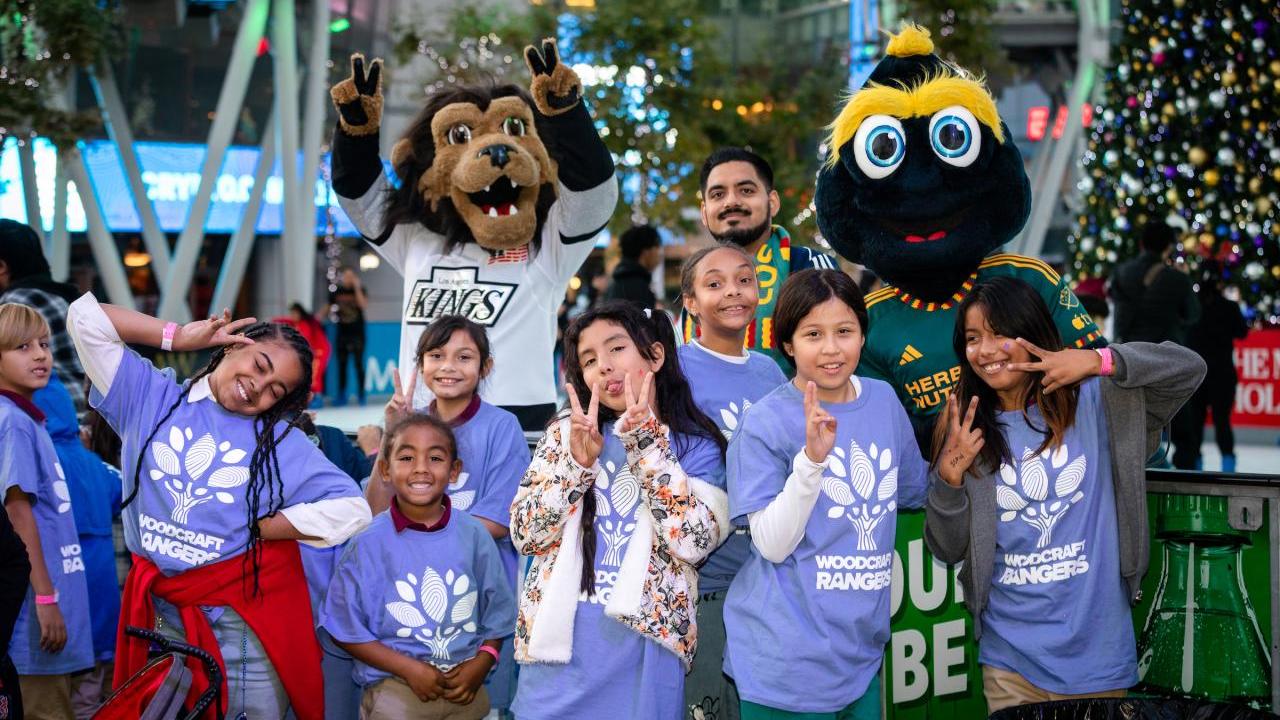 Children pose with LA Kings mascot Bailey and LA Galaxy mascot Cozmo at AEG's community holiday party at Peacock Theater at L.A. LIVE.