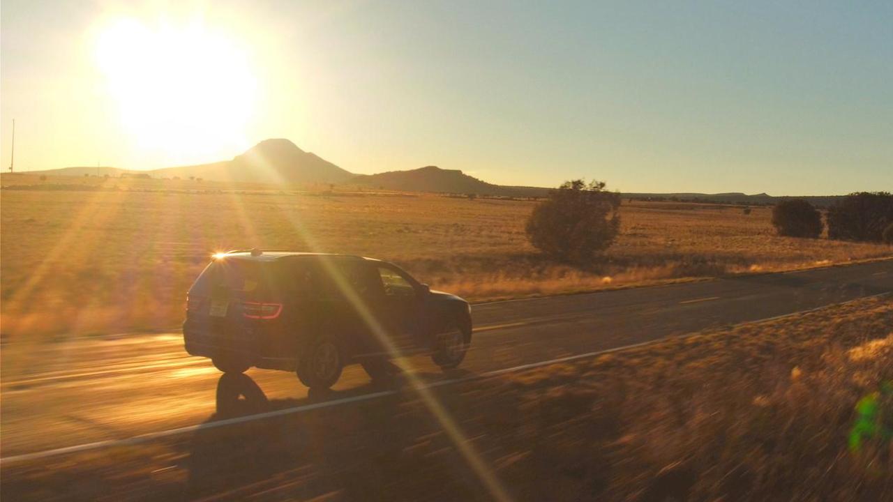car driving along a road with the sun setting