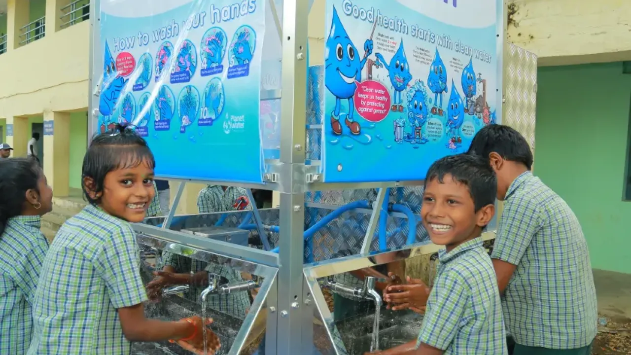 School students washing their hands under a running tap from the AquaTower system