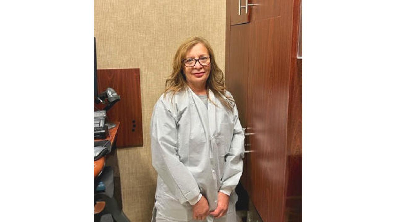 Sandra Reyes wearing a white coat, stood near a cupboard 