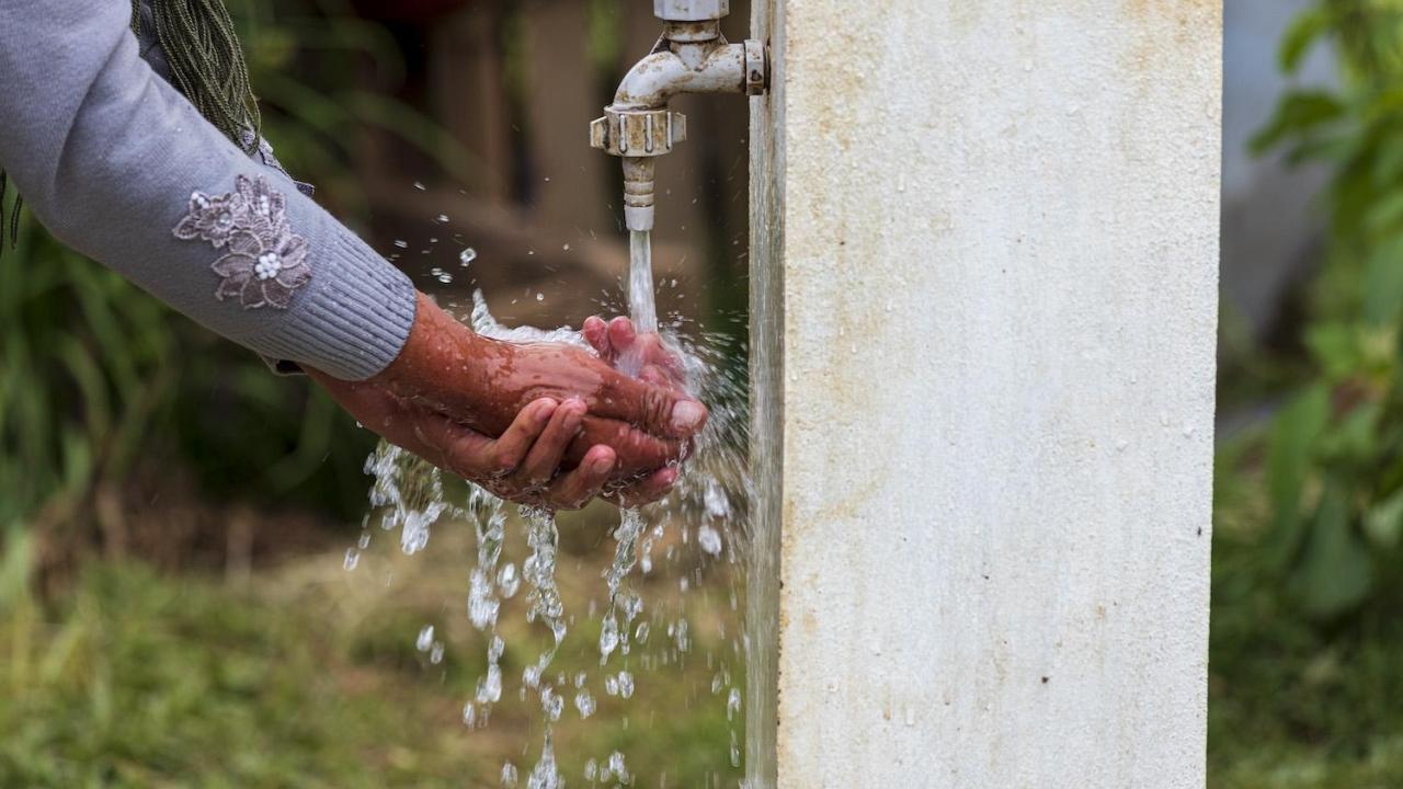 Hands being washed under outdoor faucet