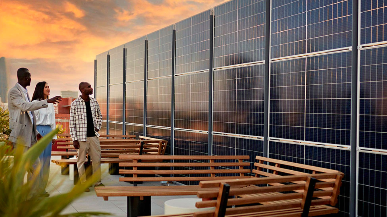 3 people standing in front of a wall of solar panels