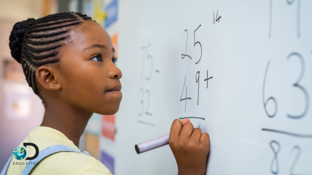a young girl doing a math equation on the white board