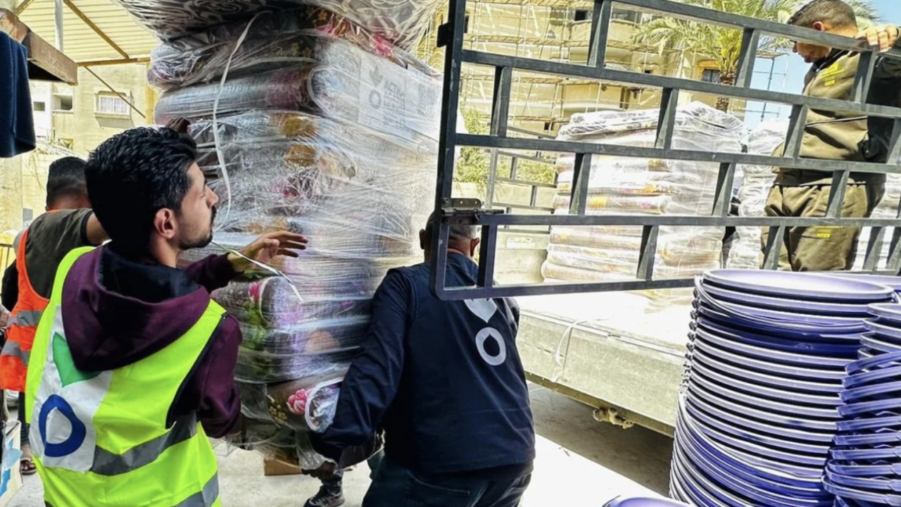 Three people moving heavy supplies onto a truck