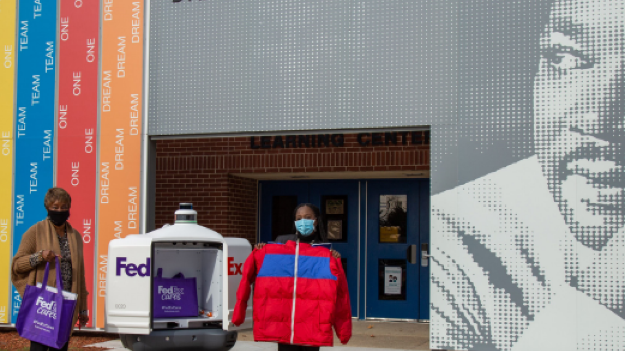 People out side of school holding up donated coats and FedEx cares bags