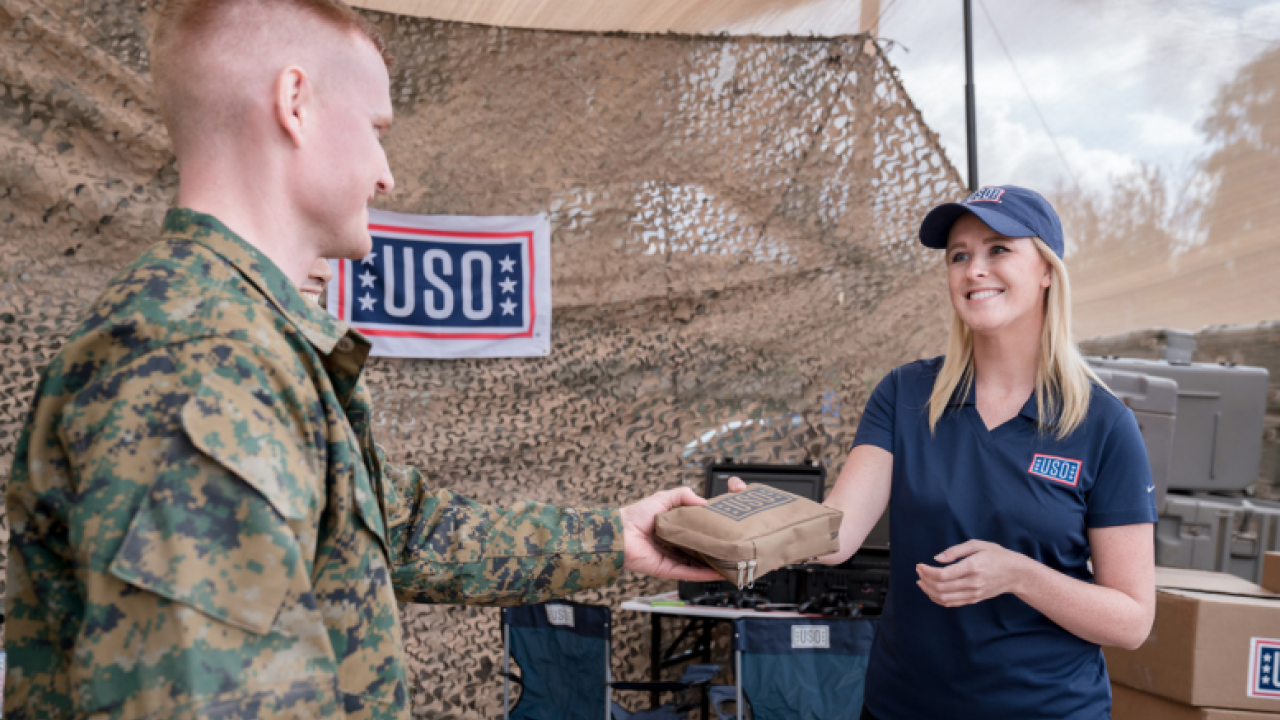 Woman from USO handing something to a soldier