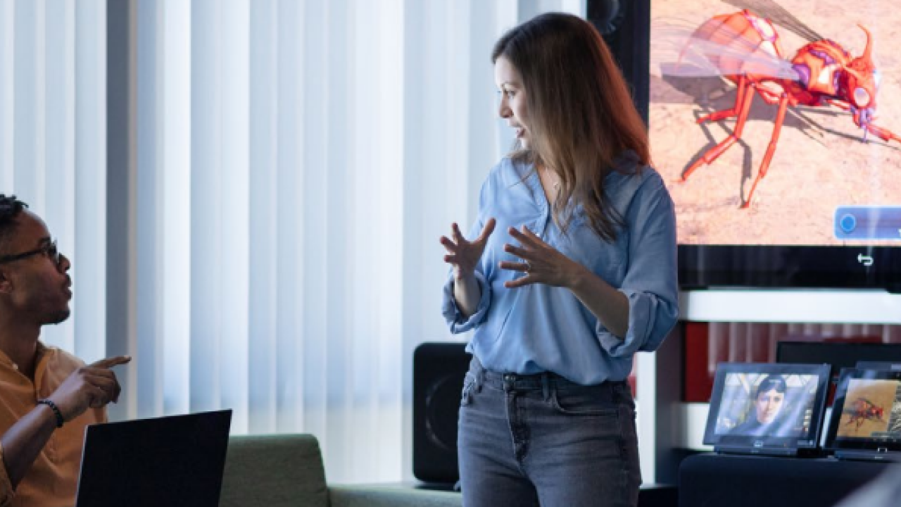 Employees talking in front of large monitor