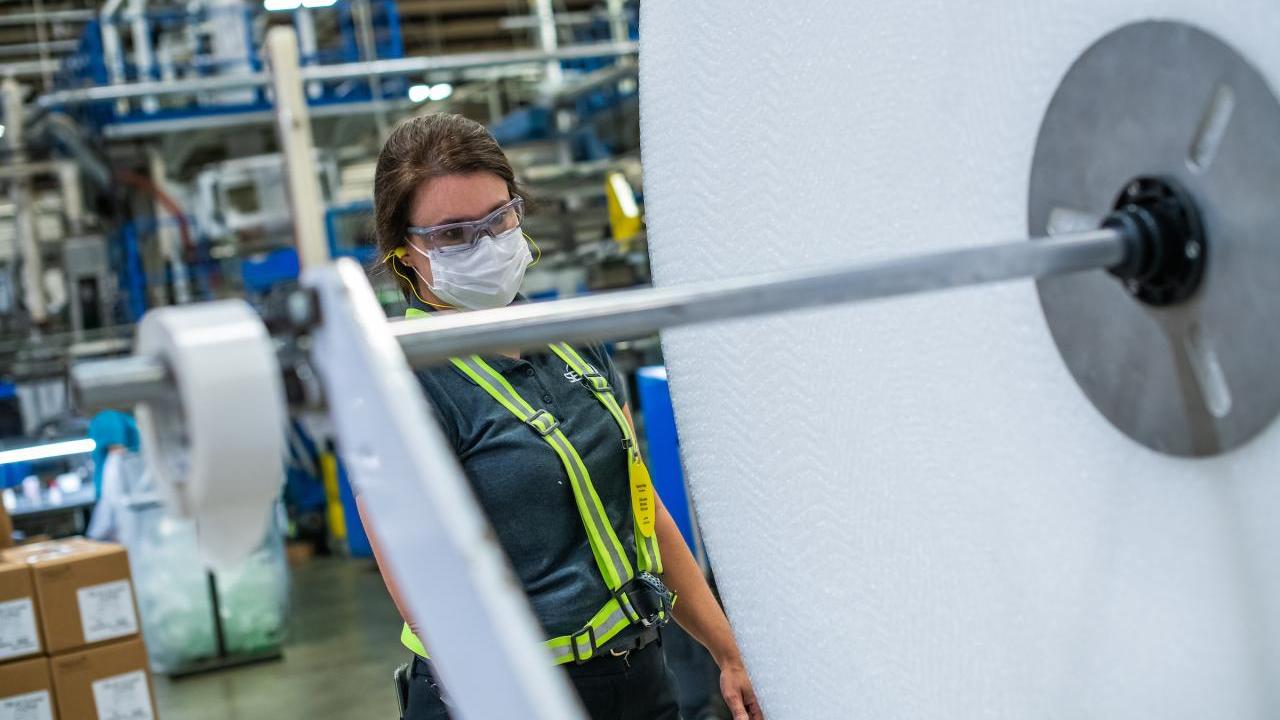 Manufacturing plant manager Karen Crisp on the shop floor looking at equipment 