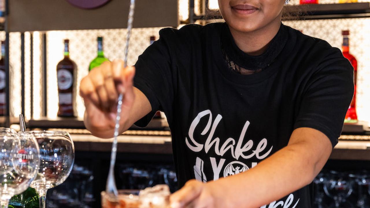A person making a drink at a bar