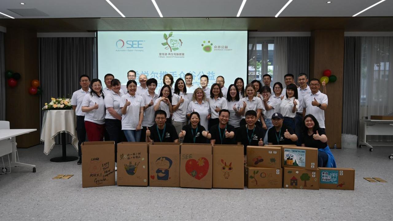A large group of people stood together behind cardboard boxes 