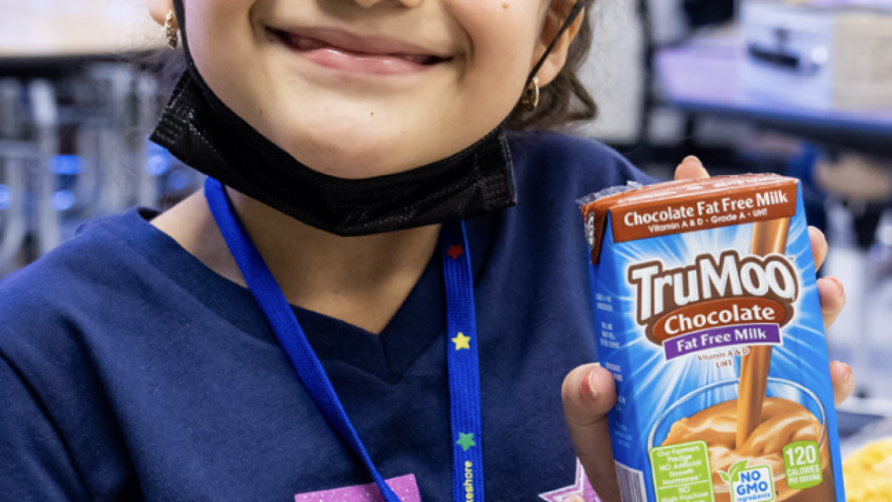 smiling child holding a container of milk