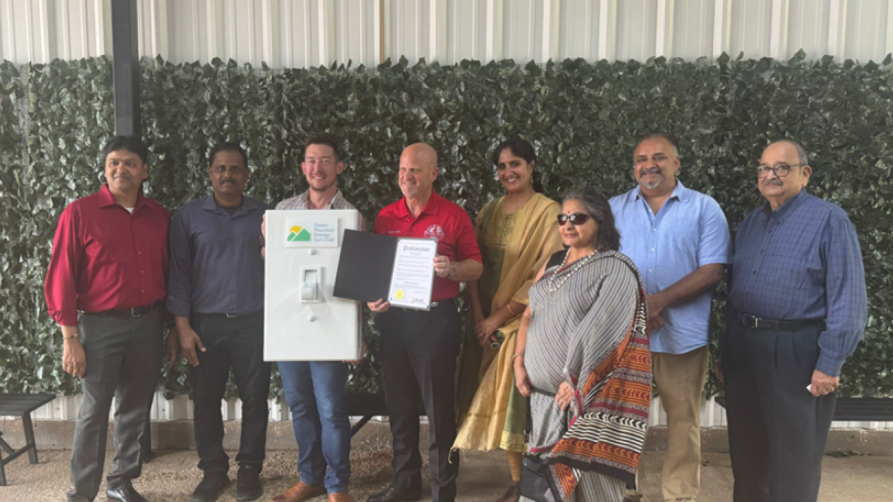 Group of diverse people standing and holding an oversized prop light switch and piece of paper