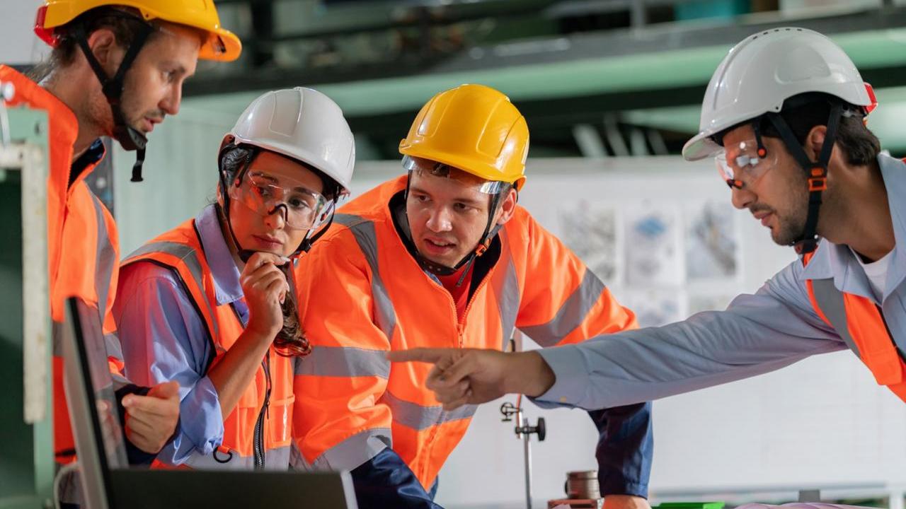 Four EHS professionals in safety gear discussing plans