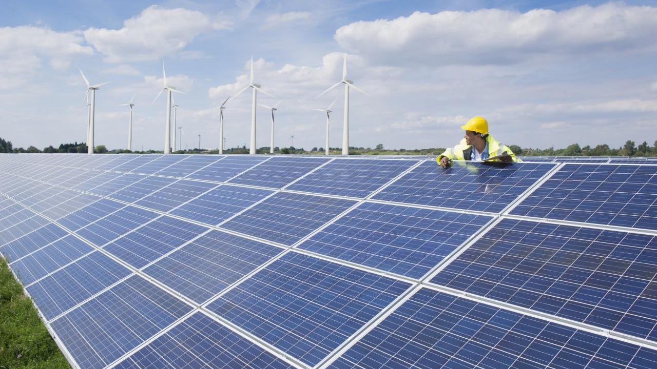 A person leant against a solar panel in a solar farm