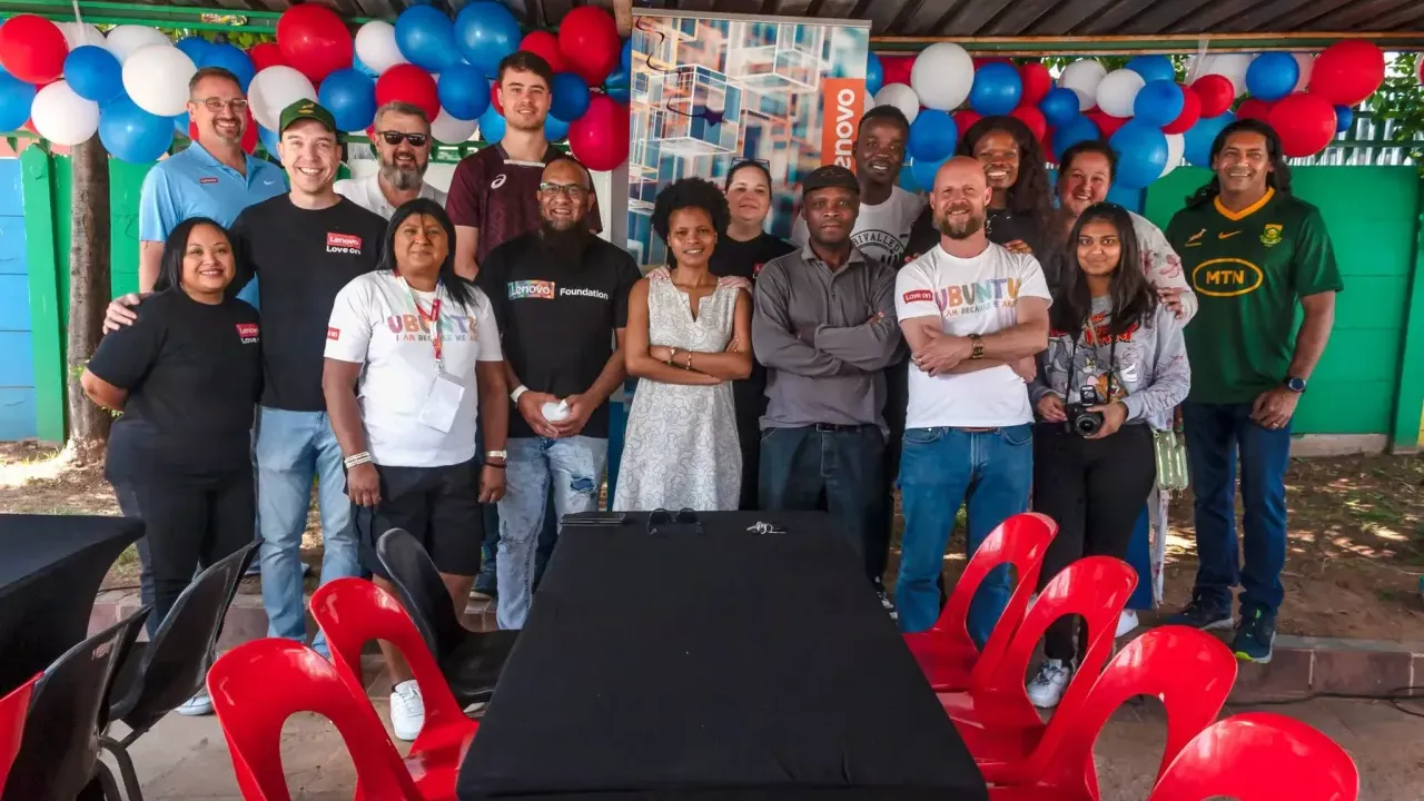 Group of people stood together for a photo, in front of a balloon garland