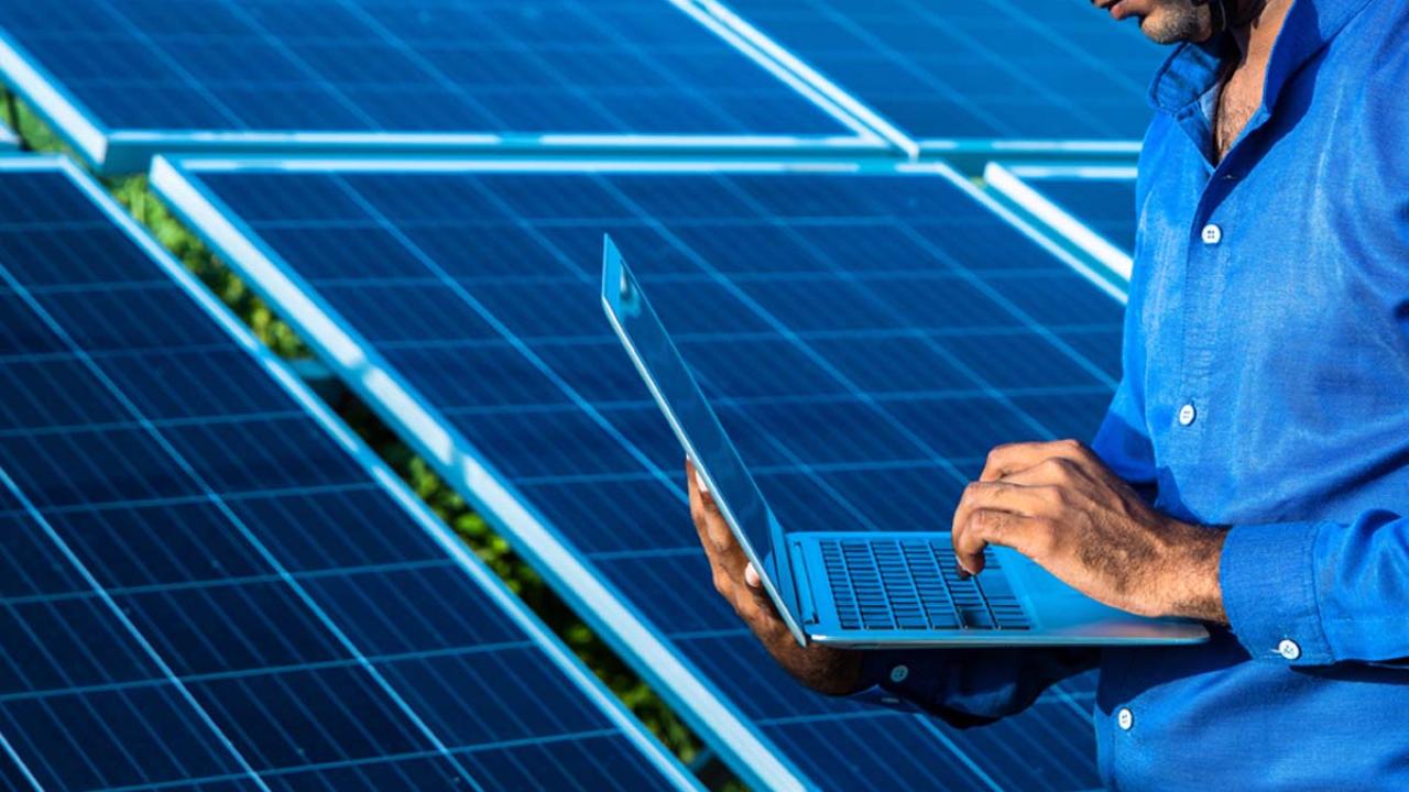 Person using laptop in front of solar panels