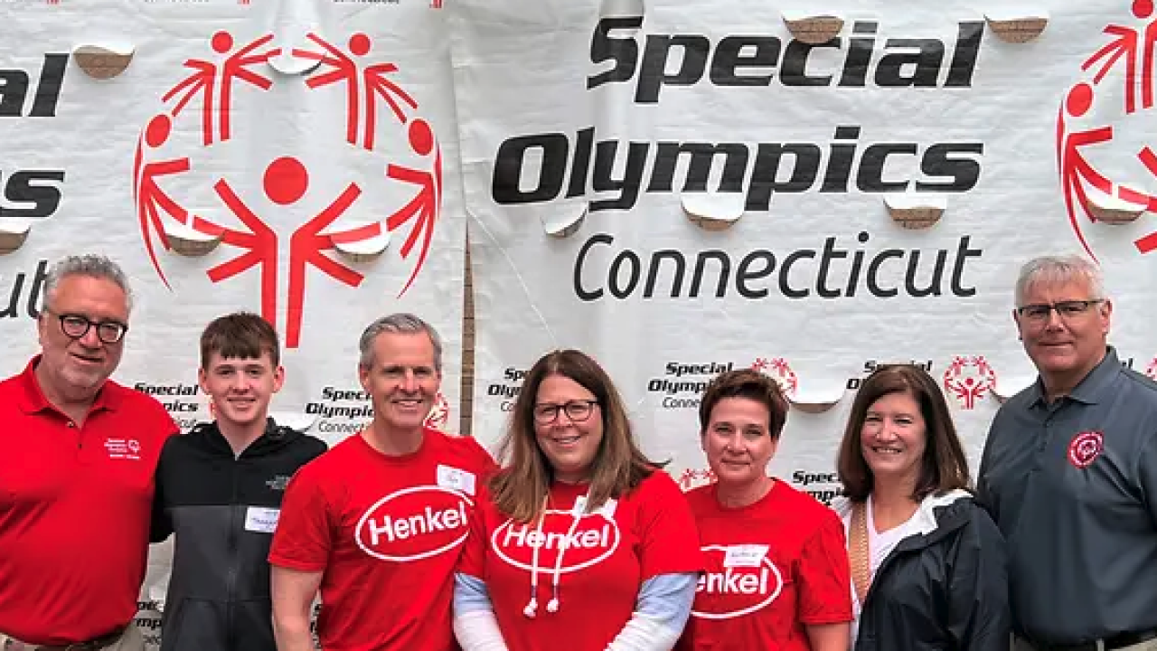 Henkel employees standing before Special Olympics Connecticut banner