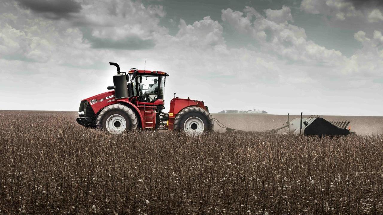 A large farm tractor harvesting crops in a field.