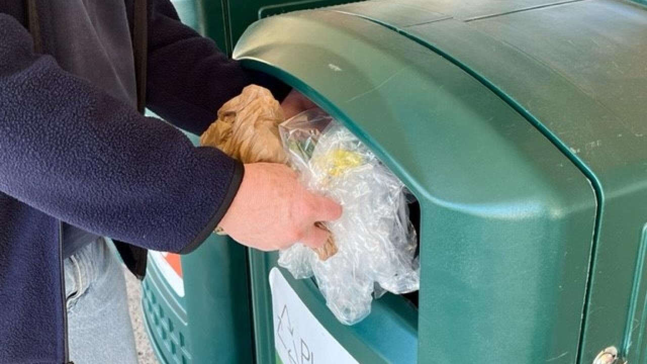 Person placing flexible plastics into a store drop-off bin for recycling.