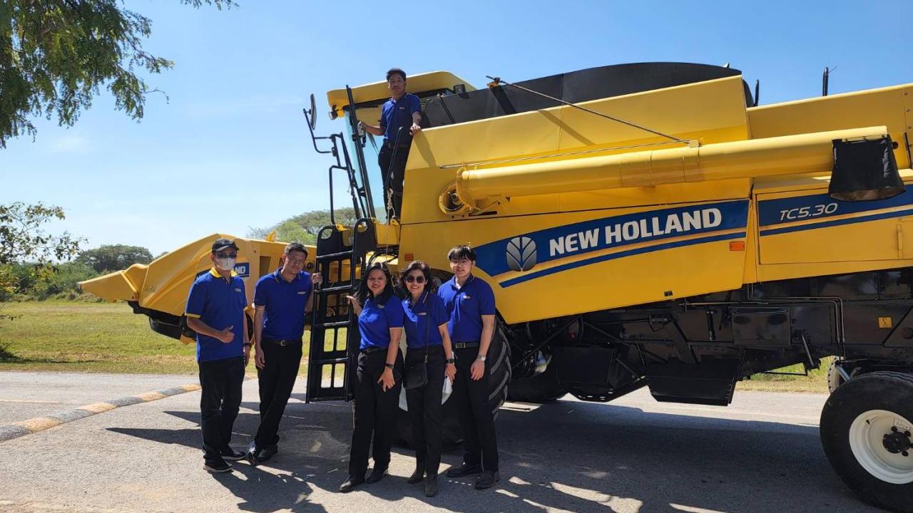 Five students standing in front of a New Holland Tractor