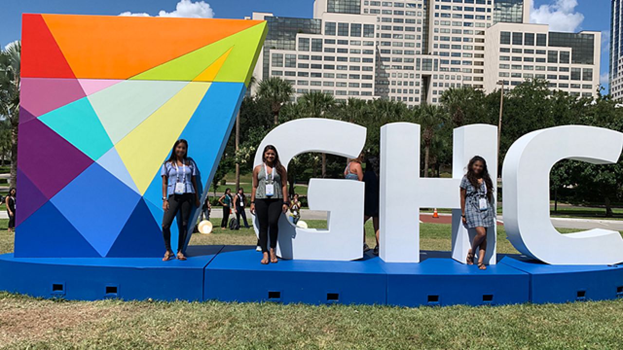 people standing in front of "GHC" statue