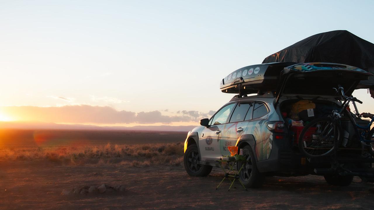 A parked car facing towards the sun setting