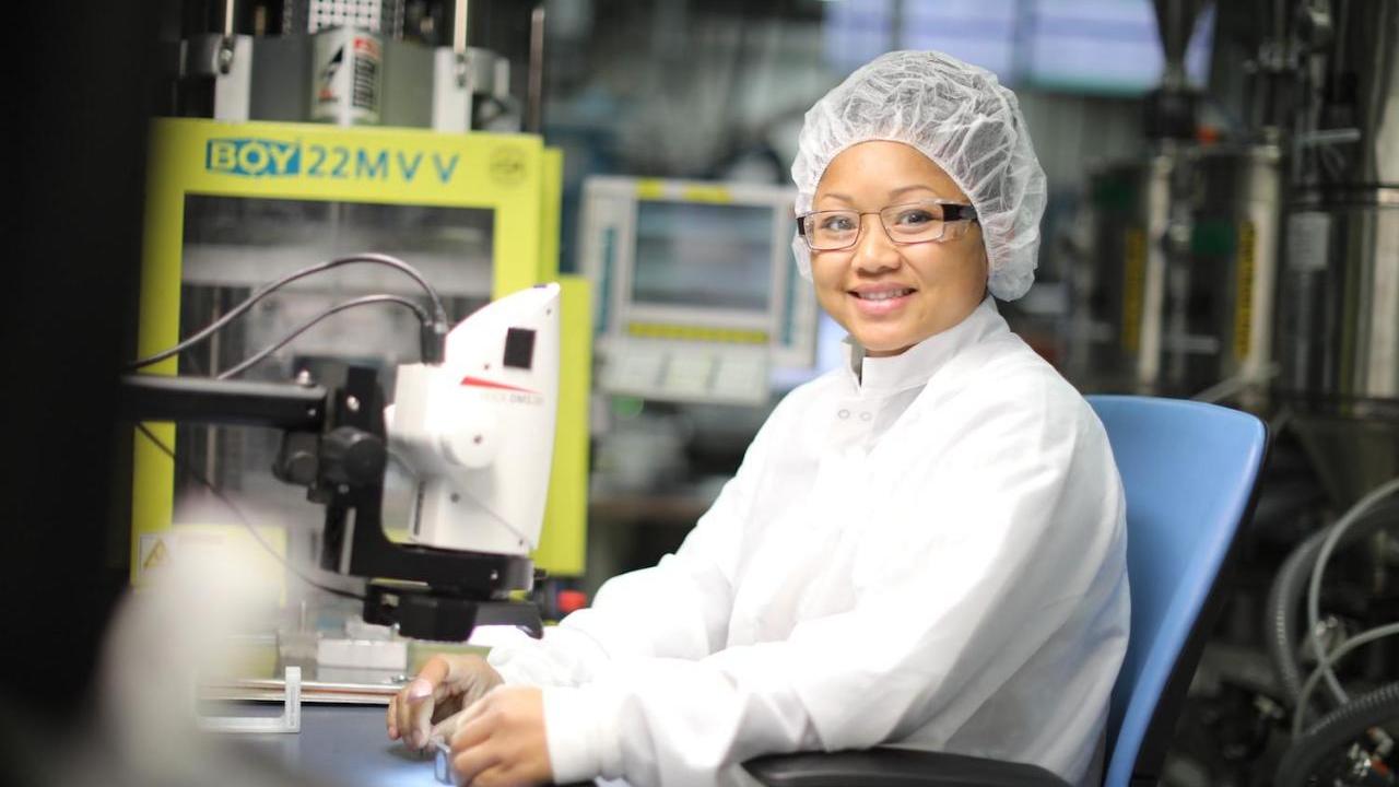 Person in white lab coat using microscope