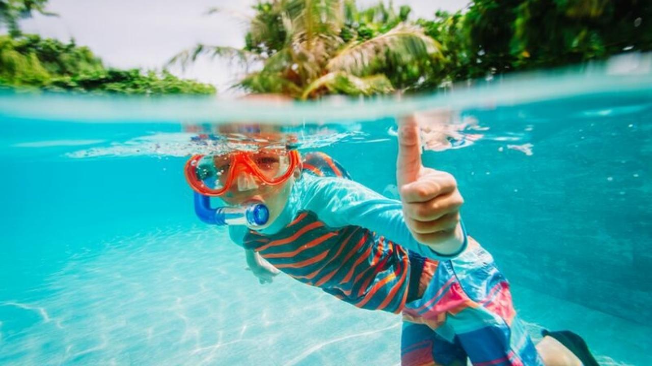 Child giving the "thumbs up" sign while swimming underwater