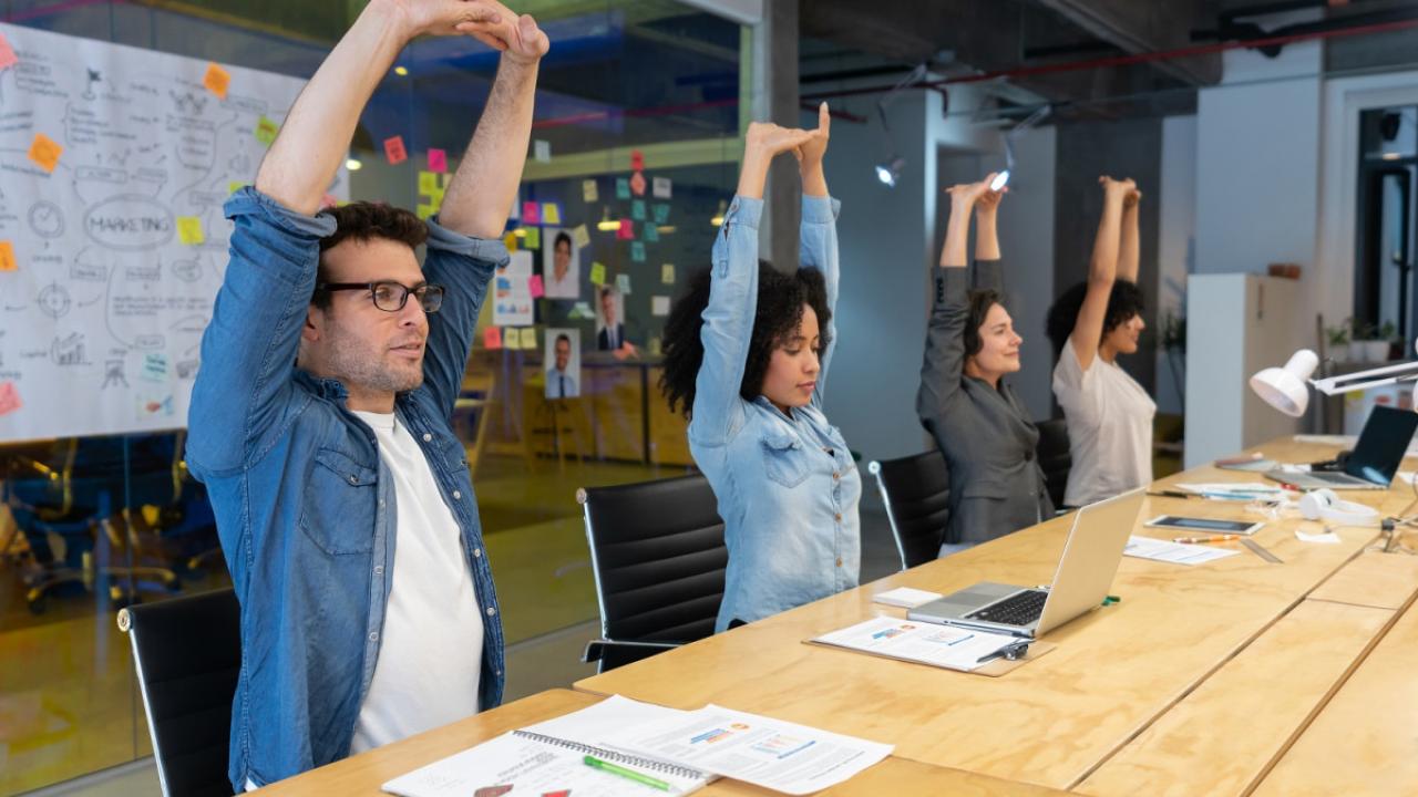 people at conference table stretching