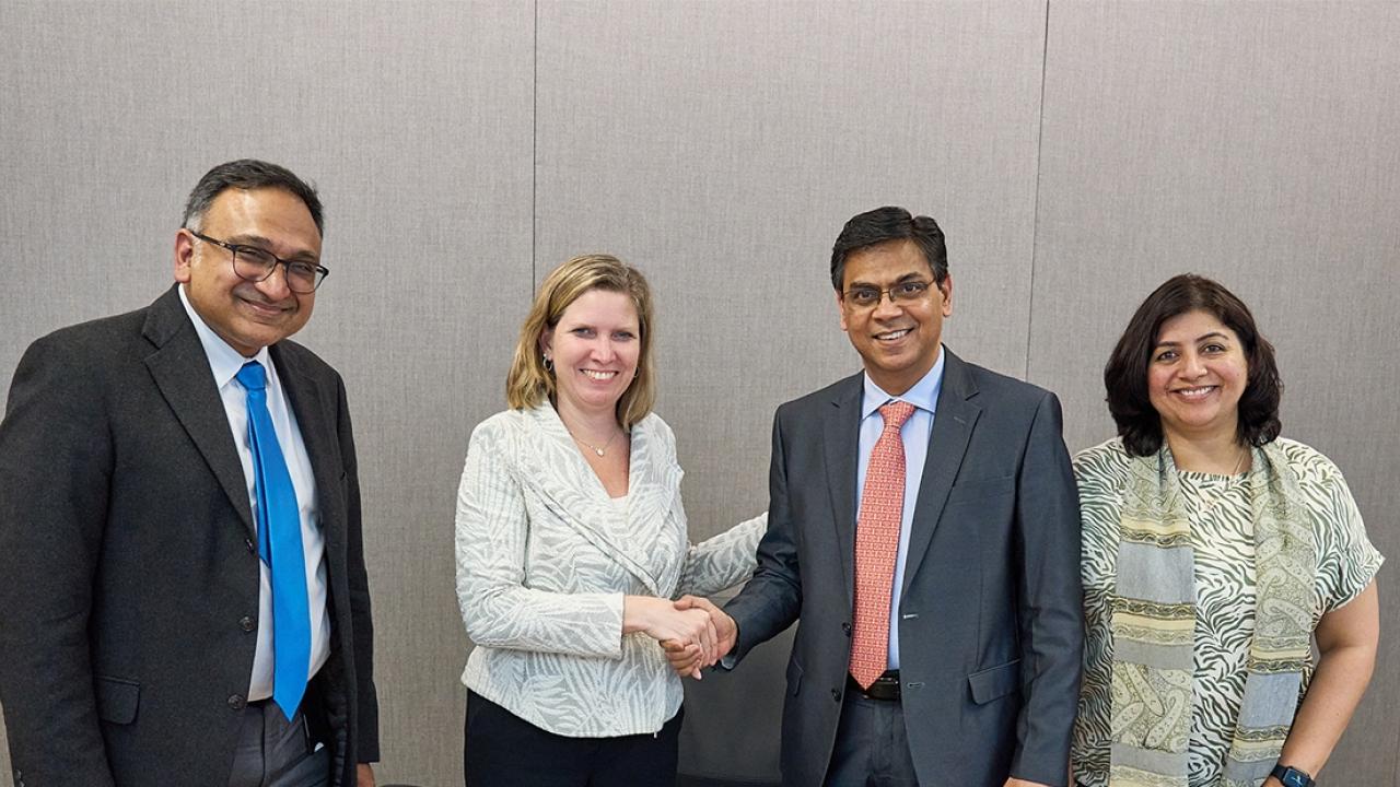 Four people smiling and shaking hands