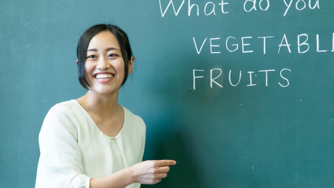 An adult stood next to a chalk board 