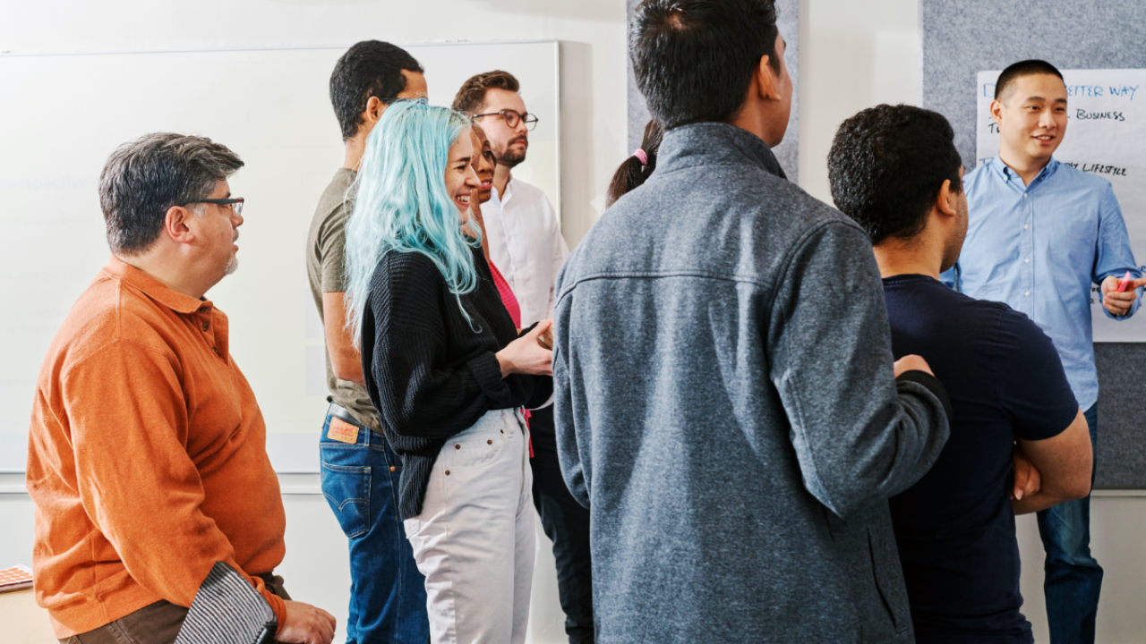 A group of people watching a presenter in front of them.
